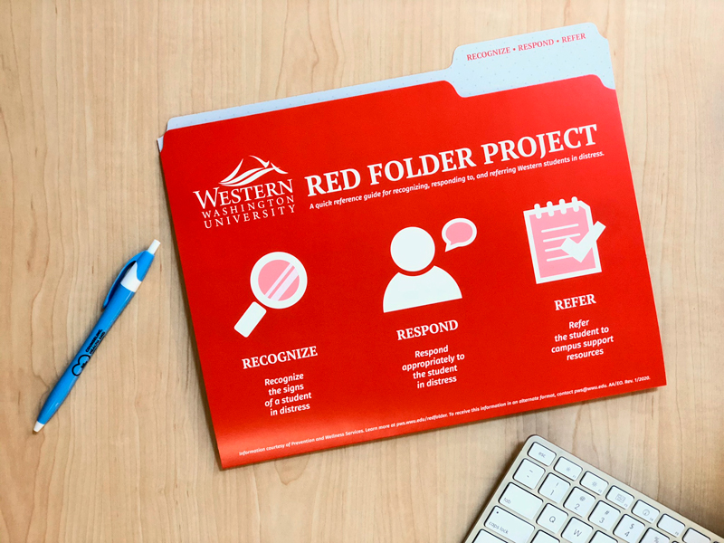 A red folder with support resources on a desk next to a pend and a pad of paper