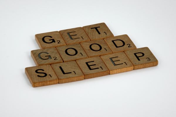 Letter tiles arranged on a white table top to read "Get Good Sleep"