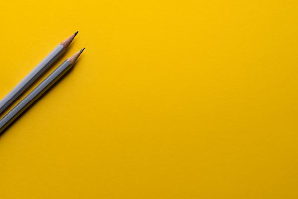Two pencils are set on the left side of a yellow background