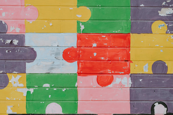 Puzzle pieces painted on a wall in yellow, pink, green, gray, light blue, and red
