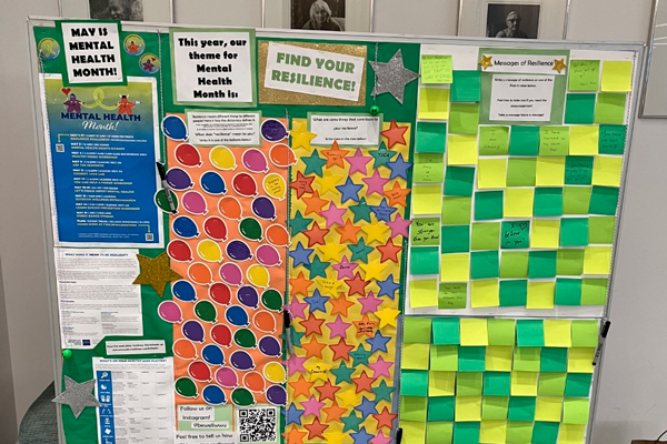 A board covered with sticky notes and messages about resilience and mental health month
