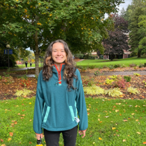 Alyssa, an Outdoor Wellness Mentor, stands outdoors smiling