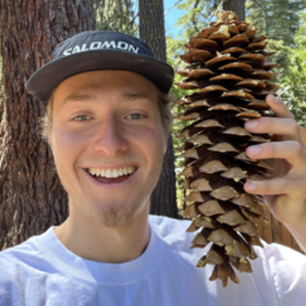 Björn, an Outdoor Wellness Mentor, smiles while holding a large pinecone