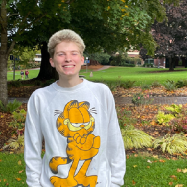 Demi, an Outdoor Wellness Mentor, smiles wearing a Garfield sweatshirt